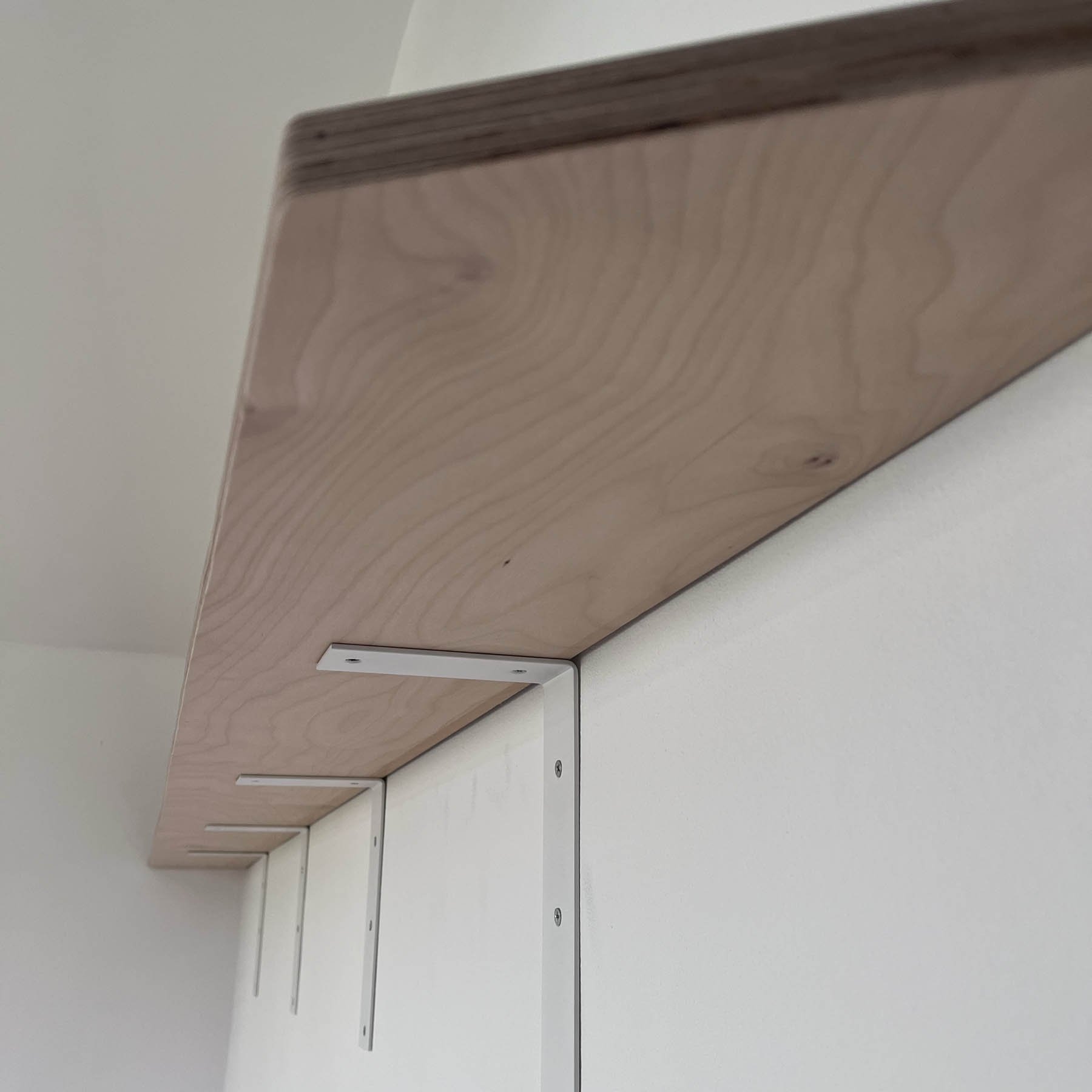 Wooden shelf fitted on white wall brackets